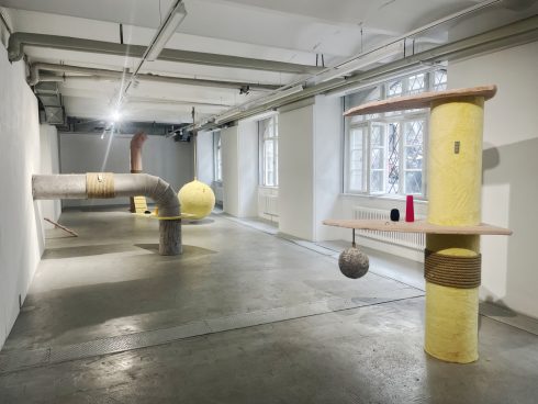Heller Ausstellungsraum mit großformatigen skulpturalen Installationen aus Rohr- und Säulenelementen.