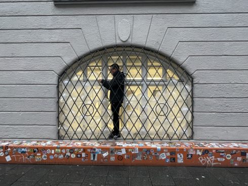 Performance vor einem Schaufenster mit weißen Luftballons hinter einem Gitter.