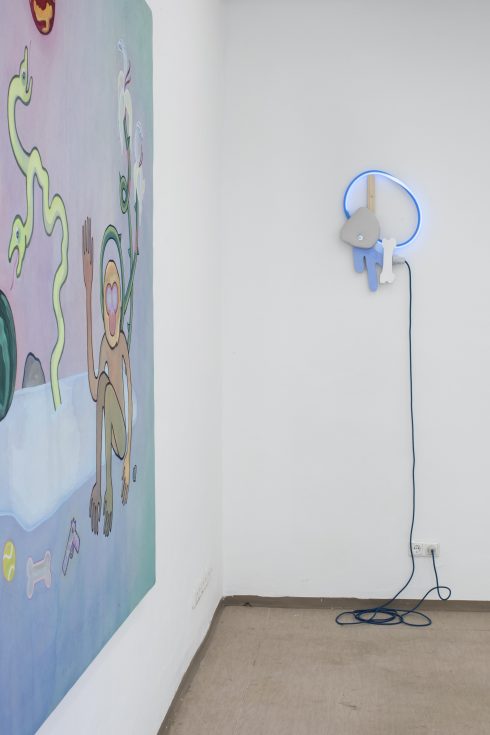 Gemälde mit figurativer Darstellung neben einer leuchtenden, wandmontierten Objektarbeit mit Kabel.