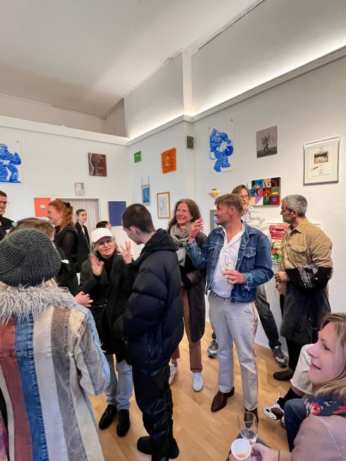 Ausstellungsraum mit vielen Besucherinnen und Besuchern und Kunstwerken an den Wänden.